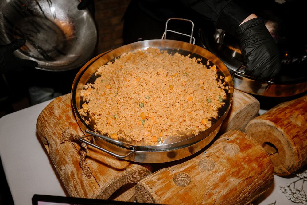 Golden fried rice served in a large stainless steel pan, displayed on rustic wooden logs at a buffet.