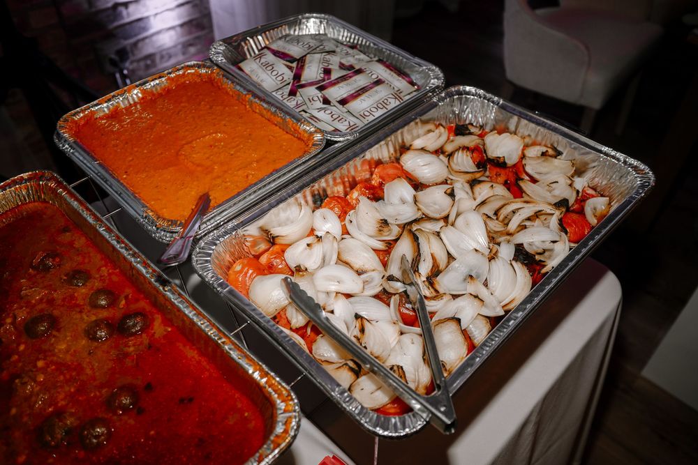 Catered buffet trays with crab legs, marinara sauce, and meatballs in foil pans.