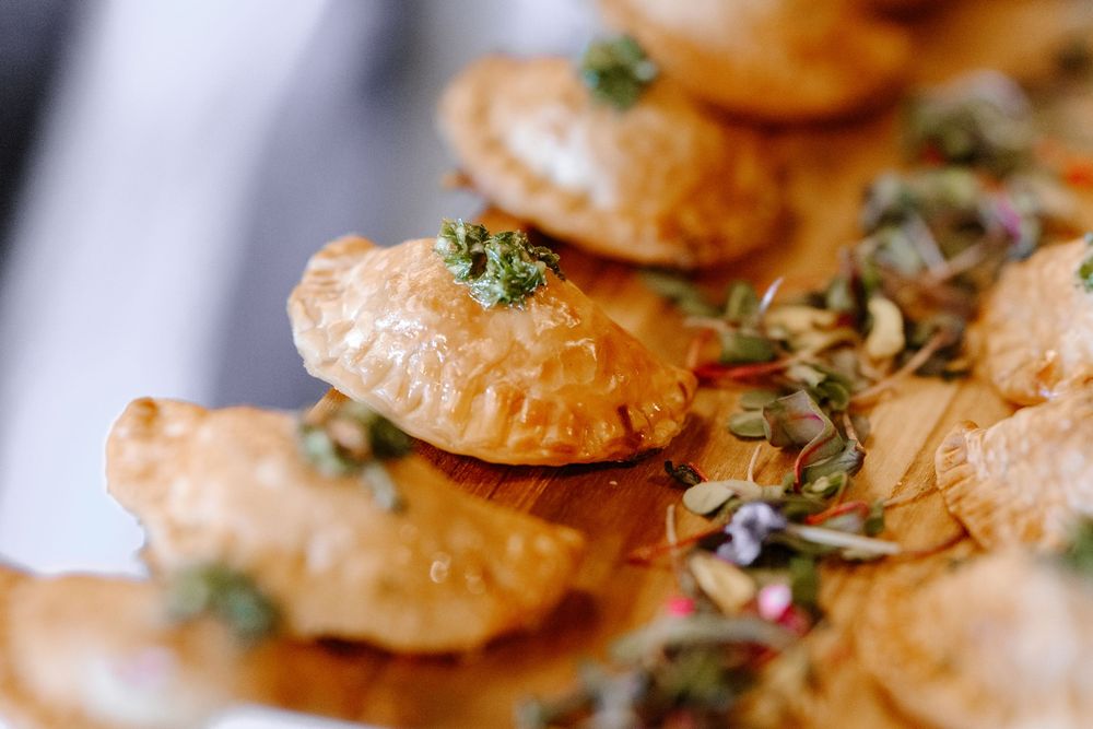 Golden baked empanadas garnished with fresh herbs on a serving platter.