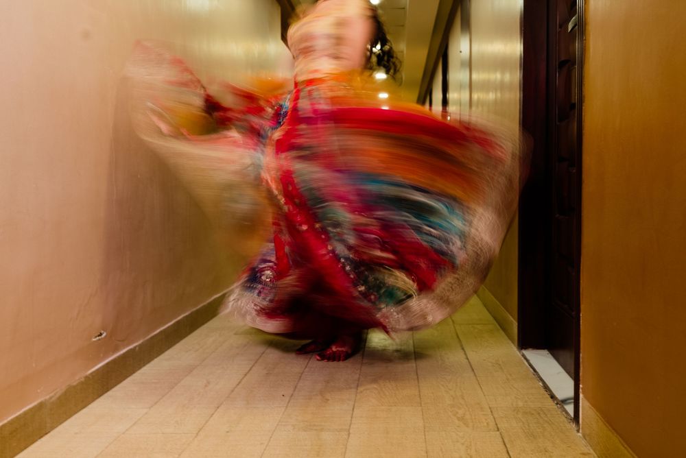 Blurred motion of a flamenco dancer in a vibrant red and multicolored swirling dress performing in a narrow hallway.