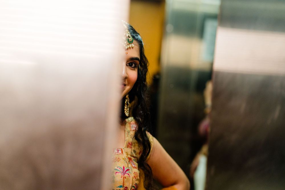 A woman in traditional Indian attire with ornate jewelry peeks around a corner in an elevator.