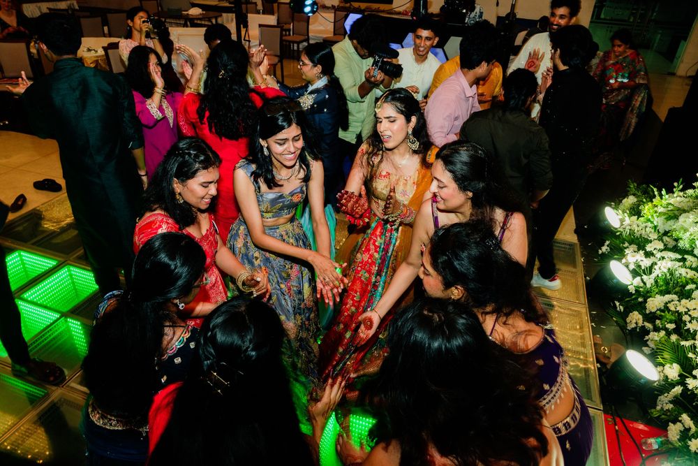 Women in colorful traditional Indian attire dancing together at a festive wedding celebration event.