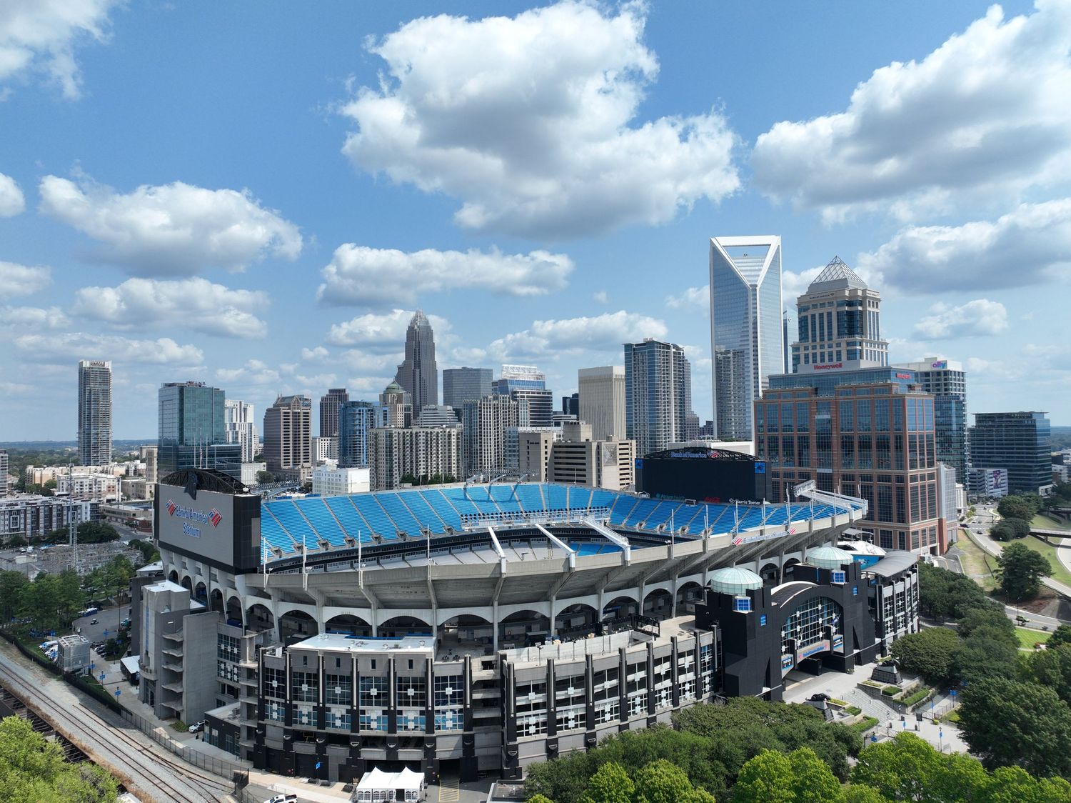 Aerial view of Bank of America Stadium in Charlotte, NC, with the city skyline and blue sky backdrop.