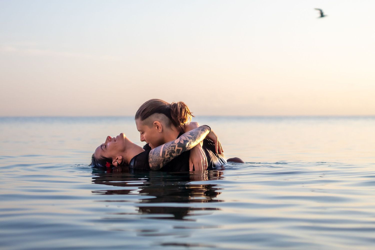 Two people share a romantic moment while floating together in calm ocean waters at sunset, lake worth beach.