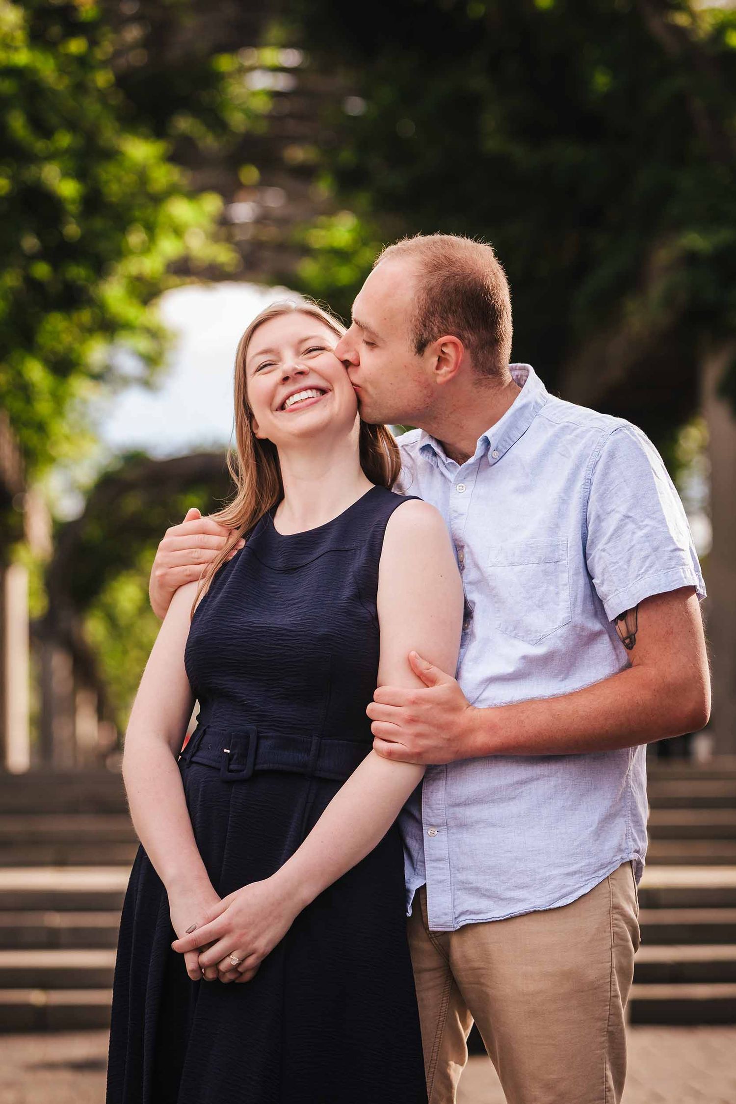 Groom-to-be kissing his fiancée's cheek near Christopher Columbus Park in Boston's North End