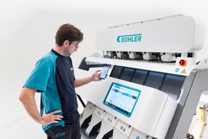 Technician operating a Buhler industrial sorting machine using a tablet interface in a modern facility.