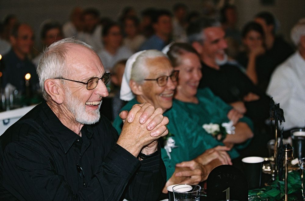 Smiling guests laughing and enjoying themselves at a formal event or banquet hall gathering.