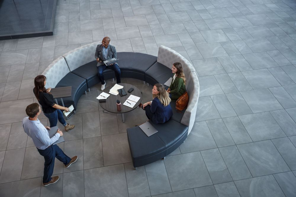 Aerial view of business professionals having a meeting on a circular sofa in a modern office lobby.