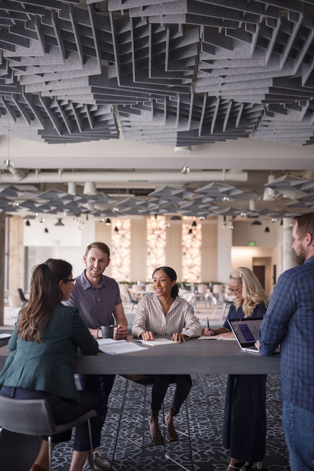Diverse business team collaborating at a modern office table with laptops, engaged in a productive group meeting discussion.
