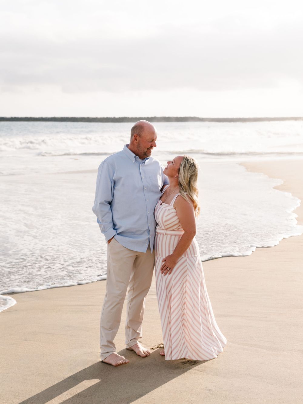 Couple walking together along the shoreline during their Newport Beach anniversary family photography session.