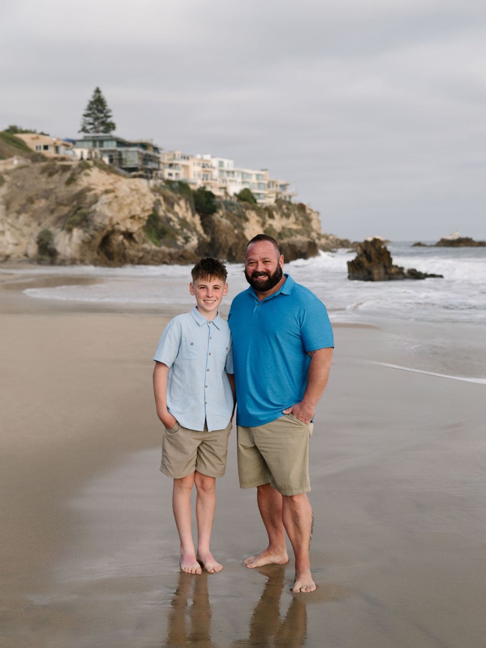 Father and son sharing a candid moment on the beach during an extended family photography session.