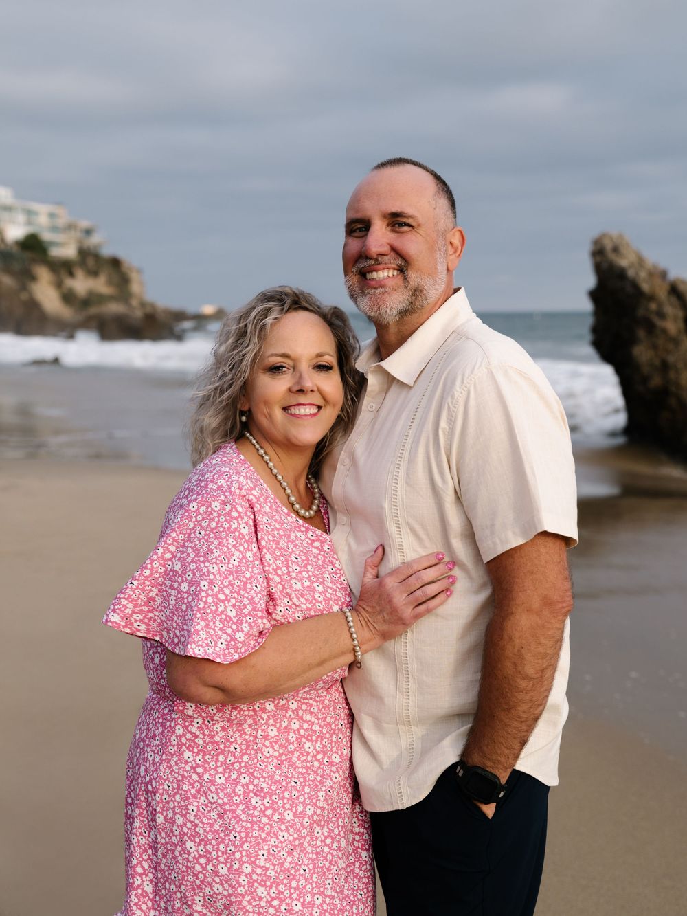 Couple smiling together on the Newport Beach shoreline during a family anniversary photo session.