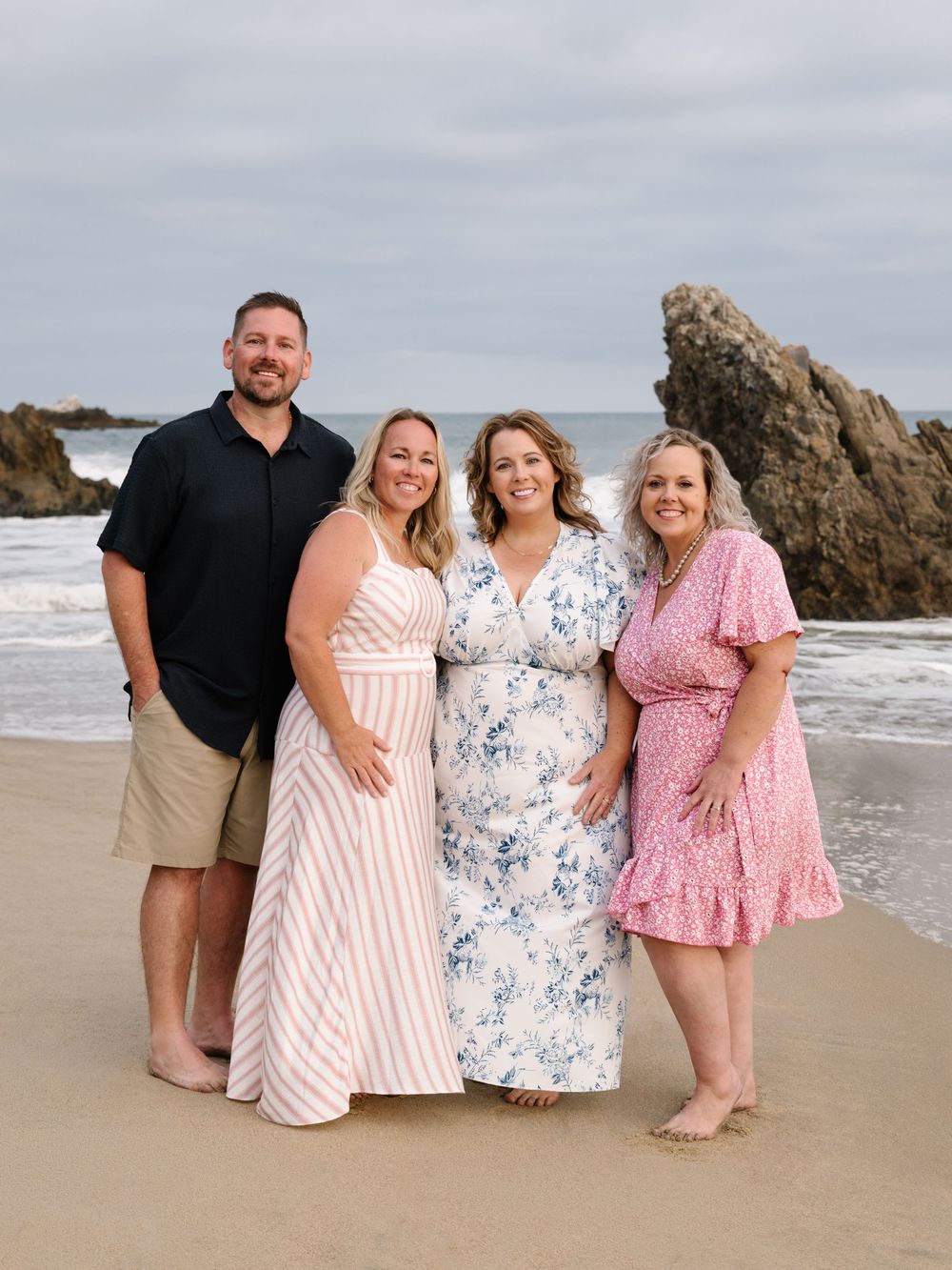 Four adult siblings together on the beach during a multigenerational family photo session.
