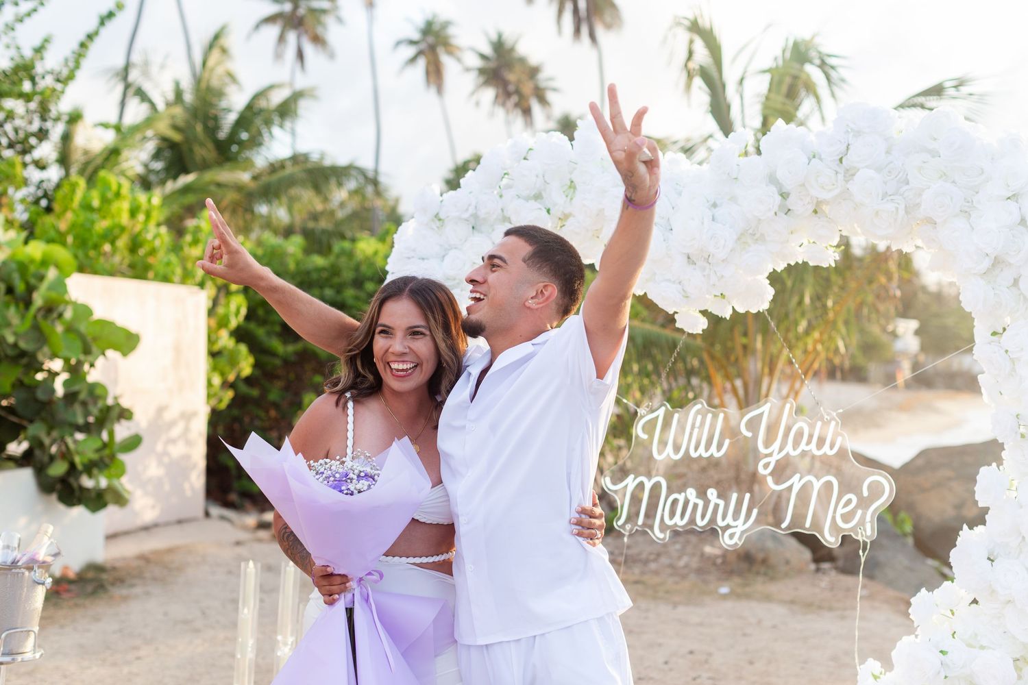 Marriage proposal. Man, woman, and decorative setup with white flower heart overlooking the ocean in Río Grande, Puerto Rico.
