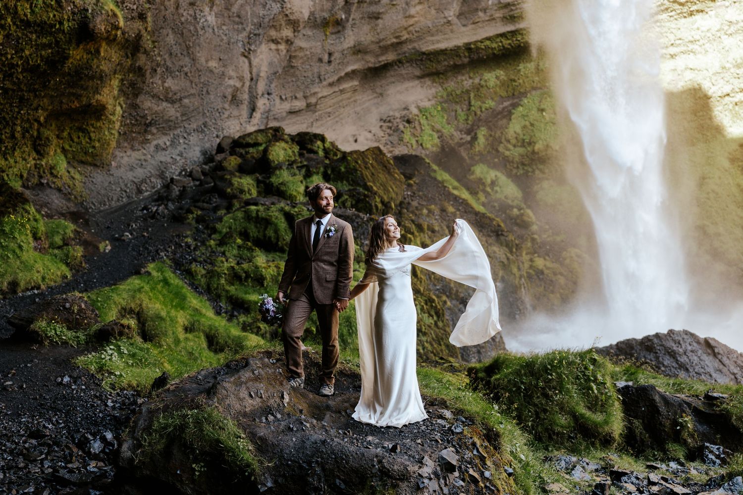 eloping couple standing side by side next to the Kvernufoss waterfall on their Iceland elopement day