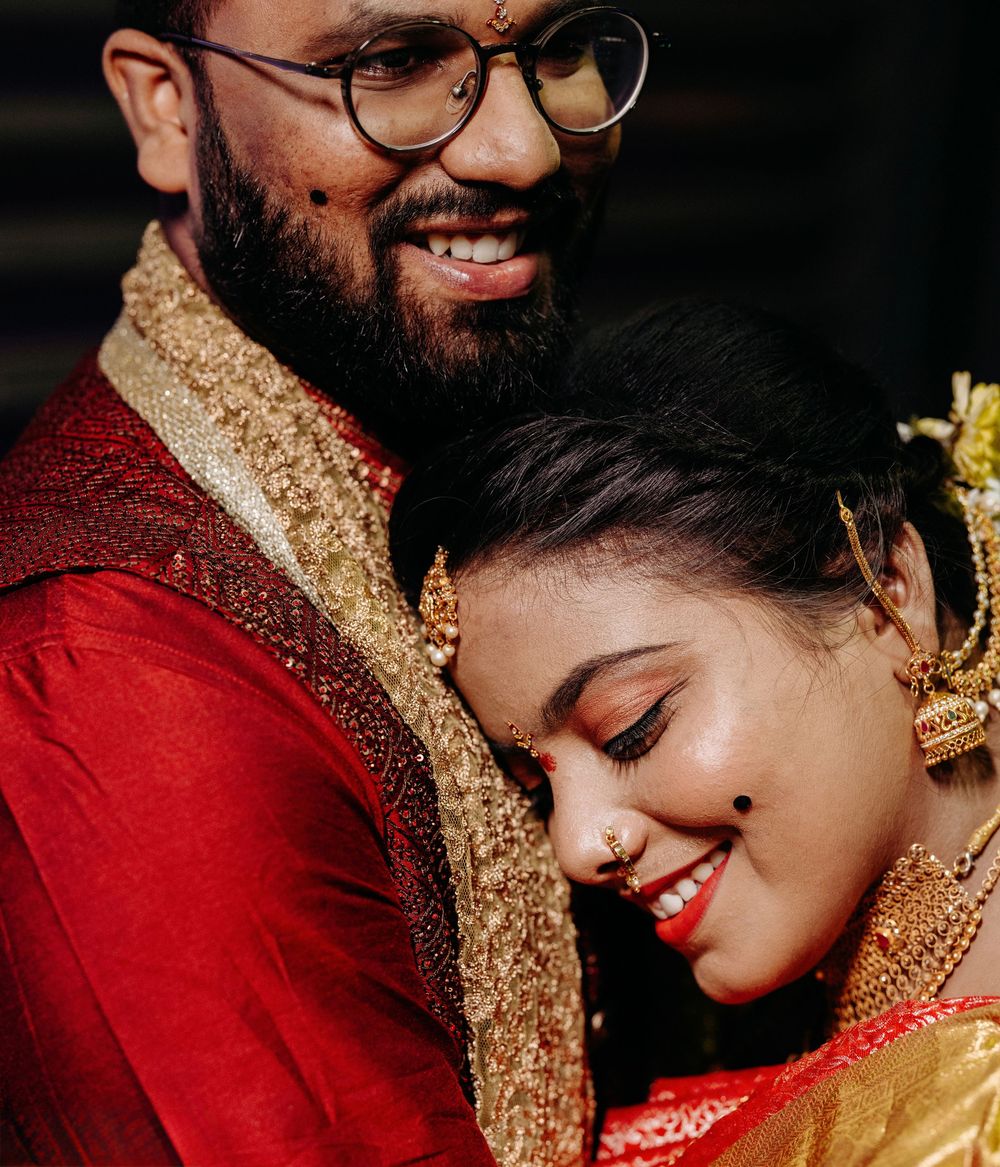 Indian couple in traditional red wedding attire sharing a tender romantic moment together.