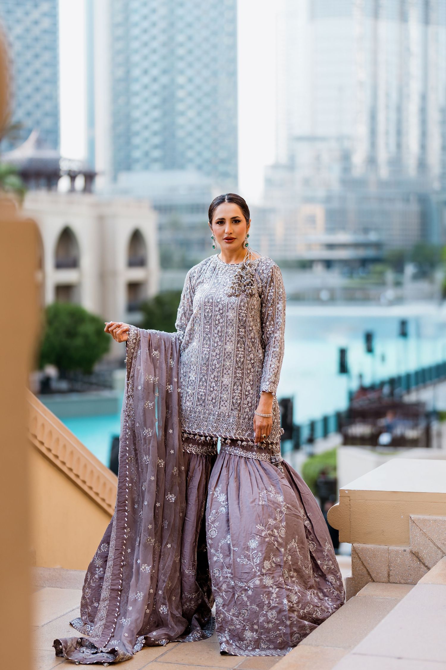Modest fashion editorial photoshoot in Dubai: model in an embroidered gharara set by the Burj Khalifa fountain