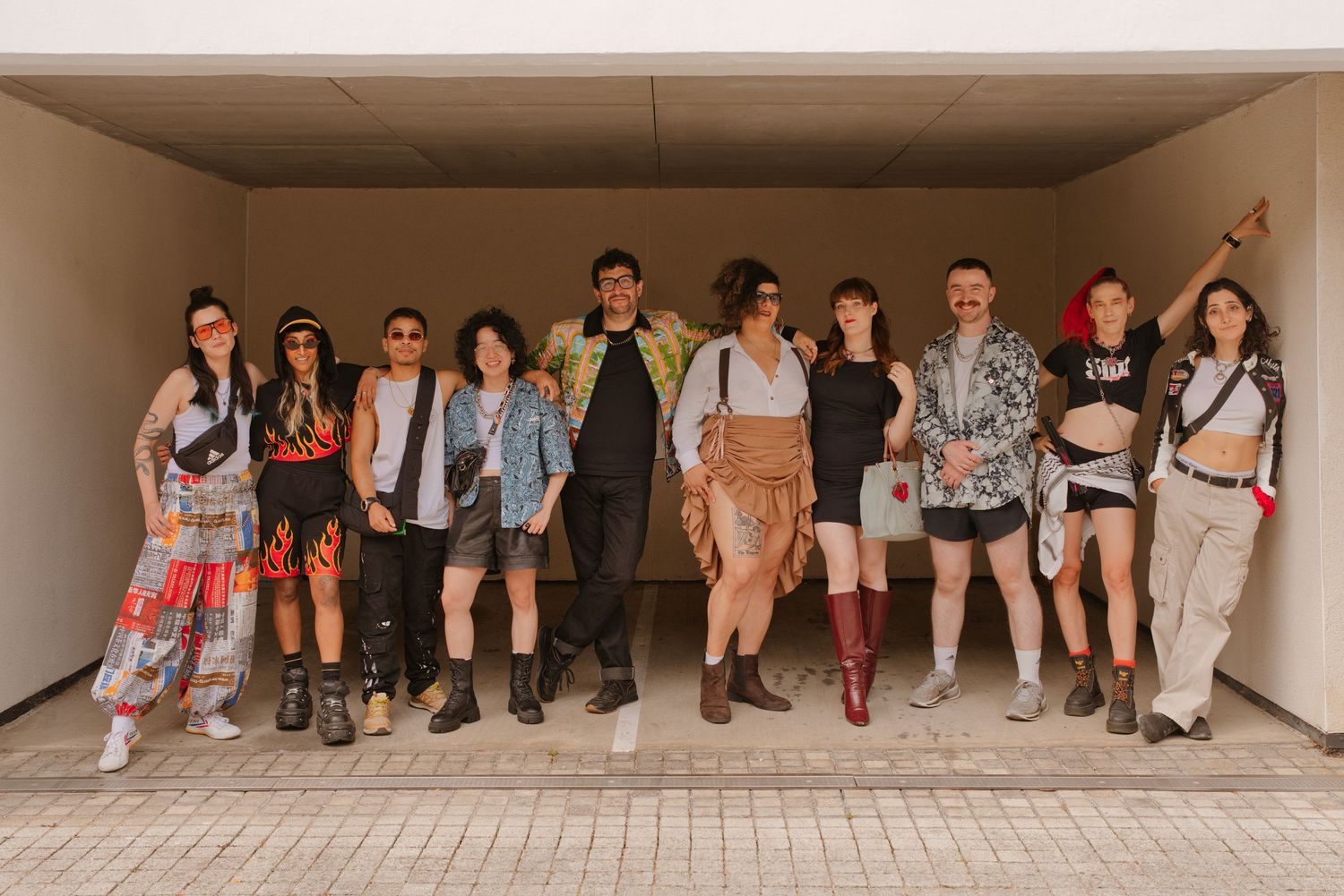 Group of stylishly dressed young people posing together in a modern outdoor corridor at a festival.