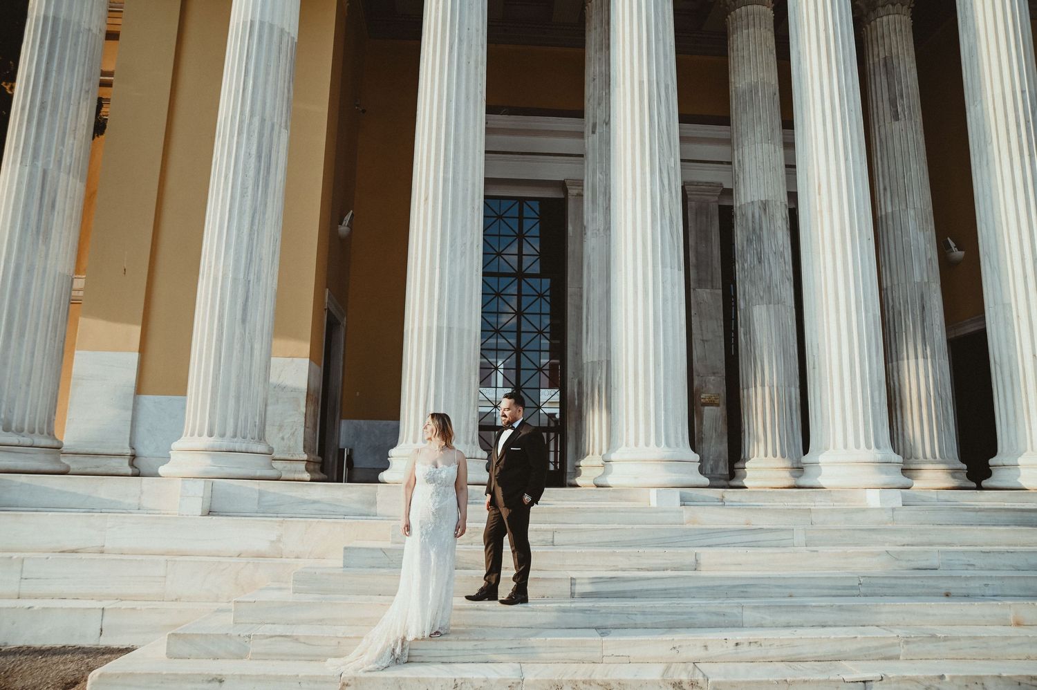 Black and white wedding photo of bride and groom gazing at each other outdoors among trees.