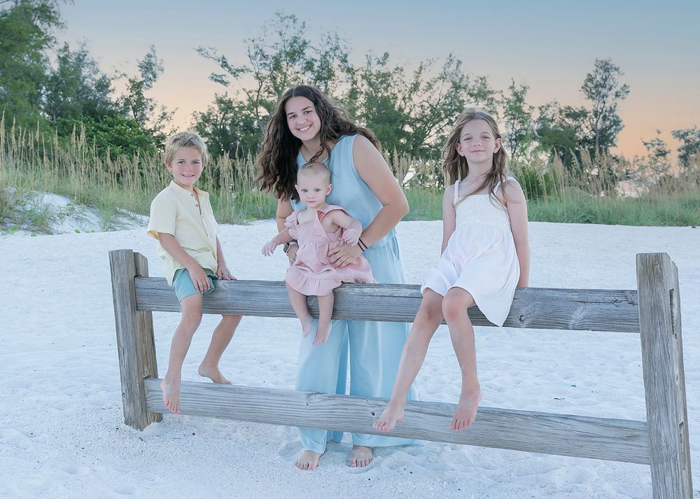 Family with little ones by a wooden beach fence, Anna Maria Island family photos