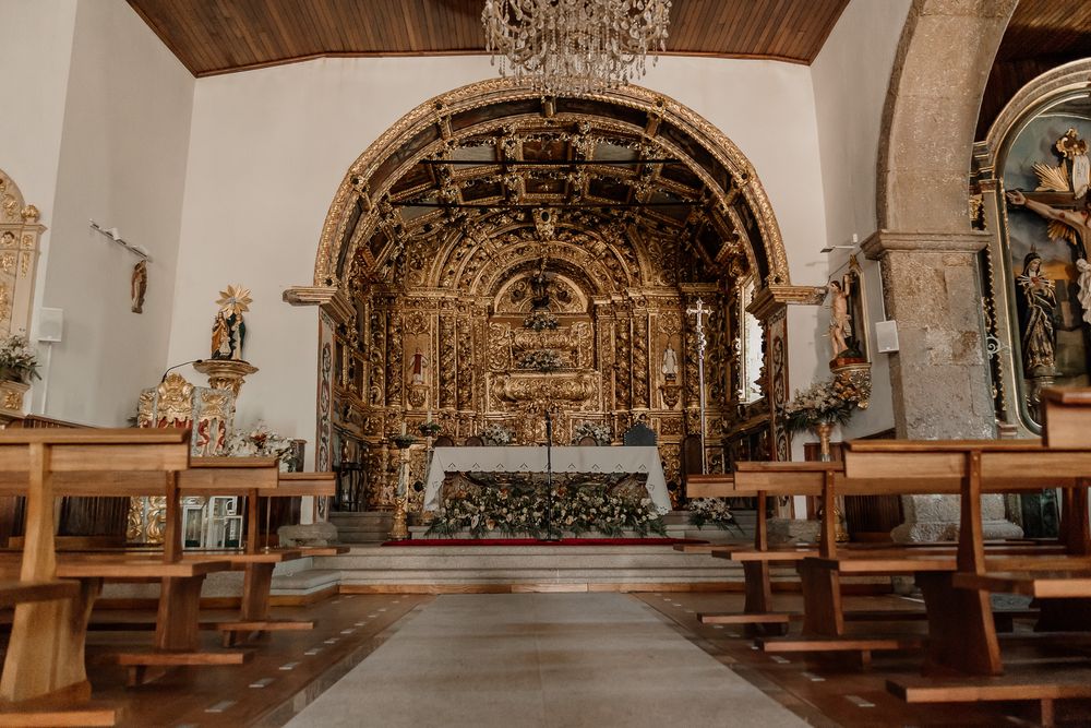 Interior of an ornate Portuguese church featuring gilded baroque altar, wooden pews, and intricate gold leaf decorations.