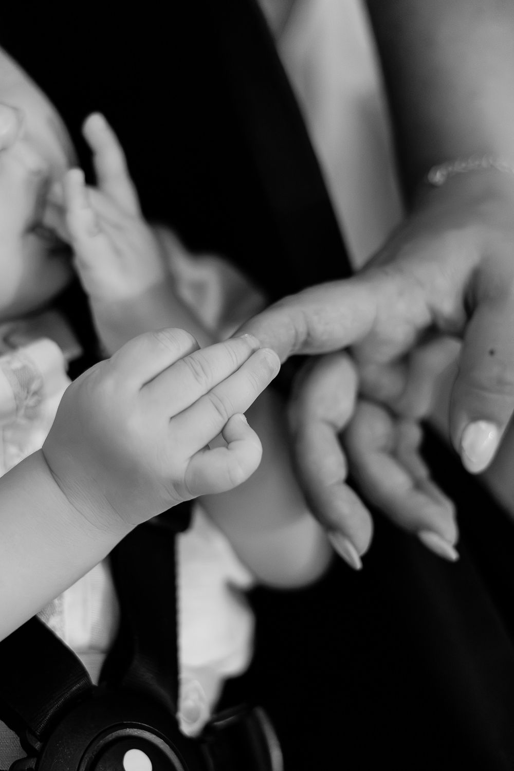 Black and white photo of a baby's hand gently touching an adult's finger, symbolizing love and connection.