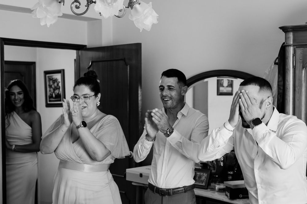 Black and white photo of emotional family members reacting with joy and tears during a wedding getting-ready moment.