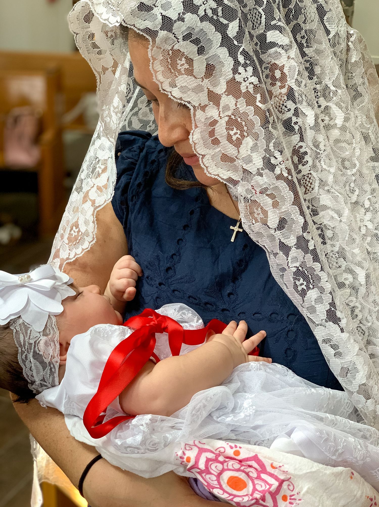 Mother in a lace mantilla holding her baby during a church baptism, Central NJ baptism photographer