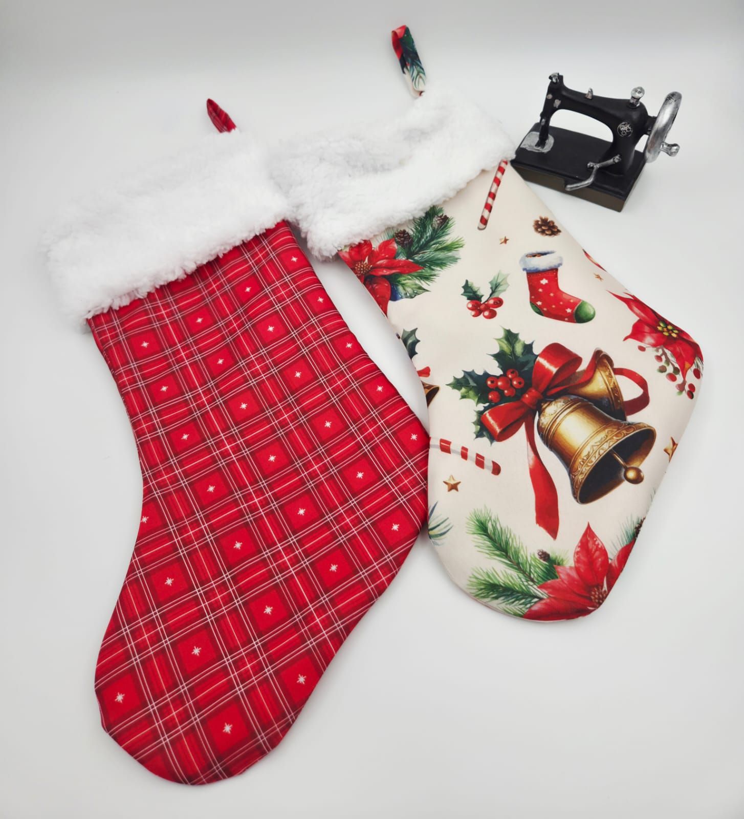 Two handmade Christmas stockings, one red plaid with white fur trim and one cream with festive holiday print, displayed together.