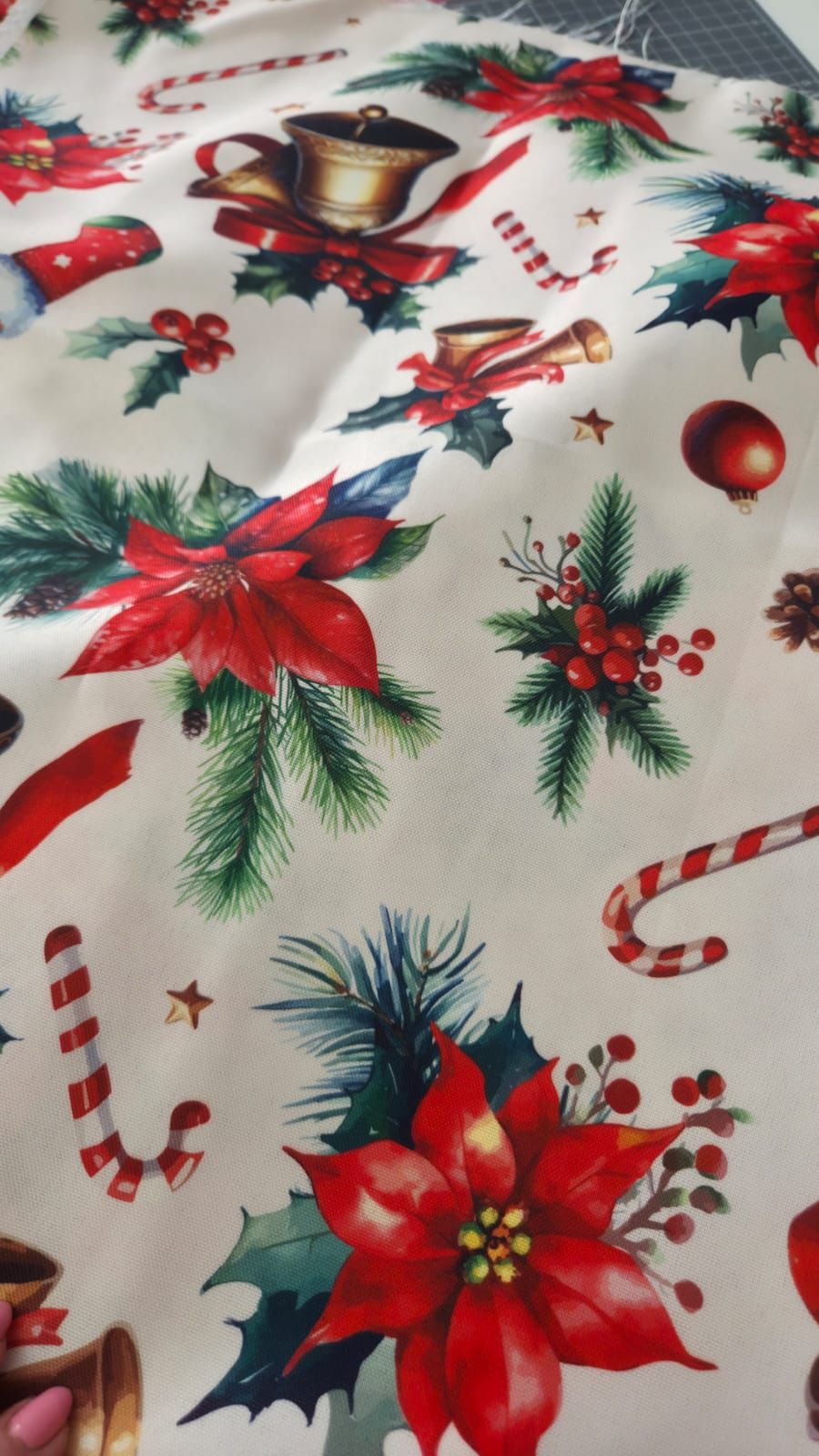 Christmas fabric featuring poinsettias, candy canes, holly berries, pine branches, and ornaments on a white background.