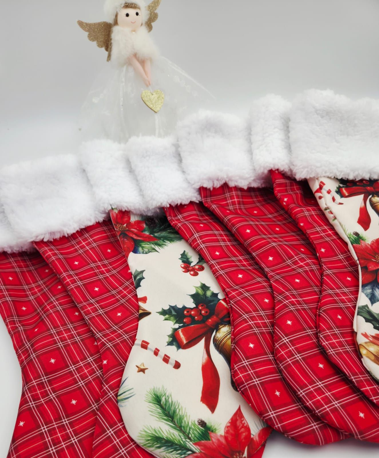 Set of red plaid and vintage print Christmas stockings with white fur cuffs displayed with angel figurine.