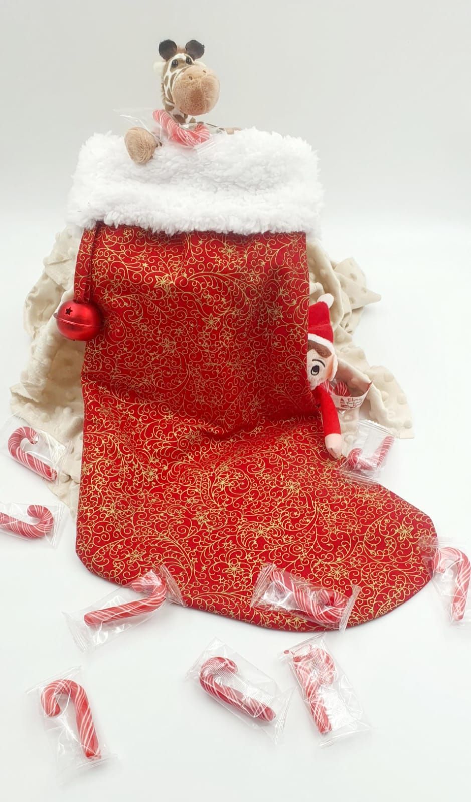 Red Christmas stocking with white fur trim, candy canes, and stuffed animals on a white background.