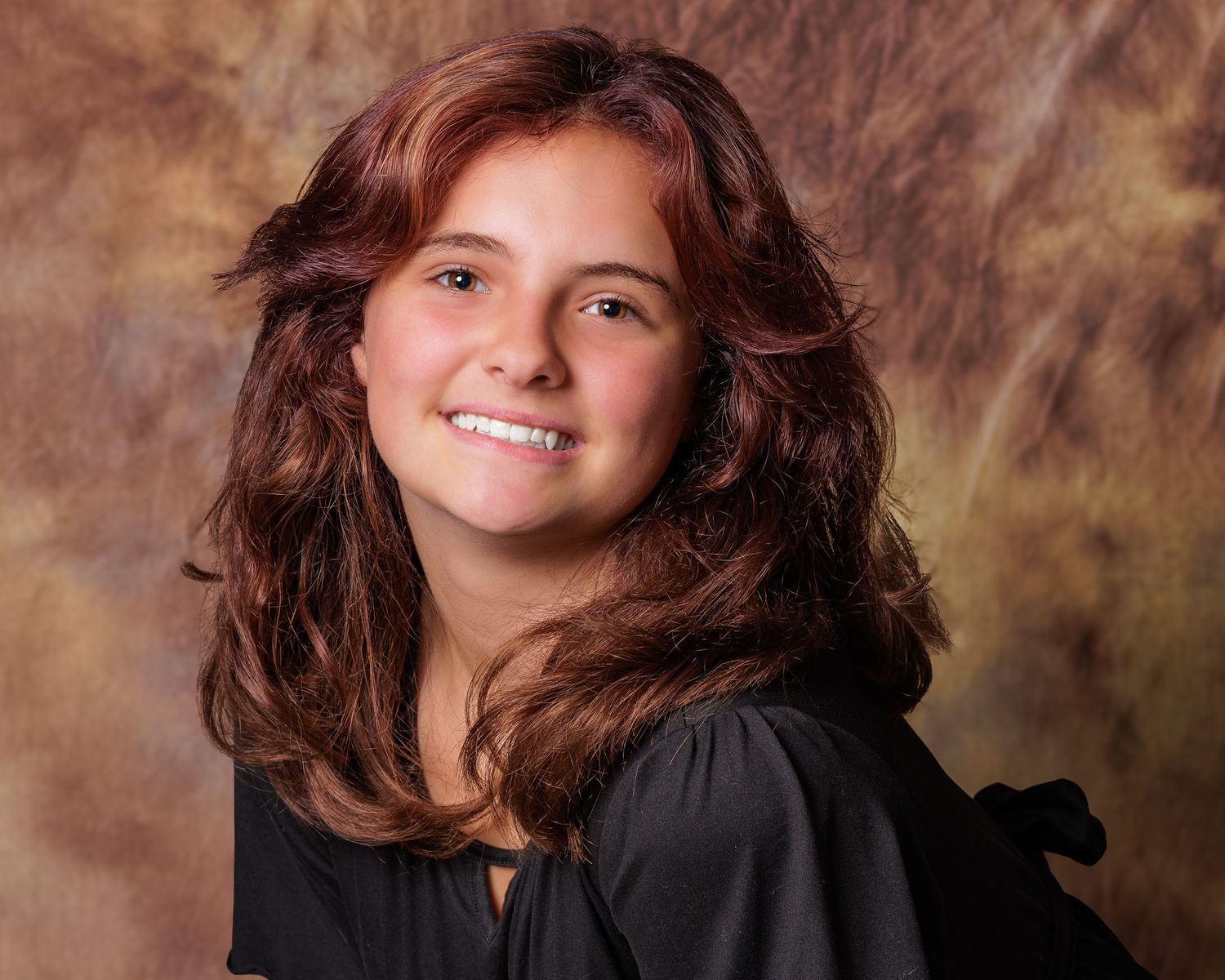 Studio portrait against brown backdrop with soft lighting and dark attire.