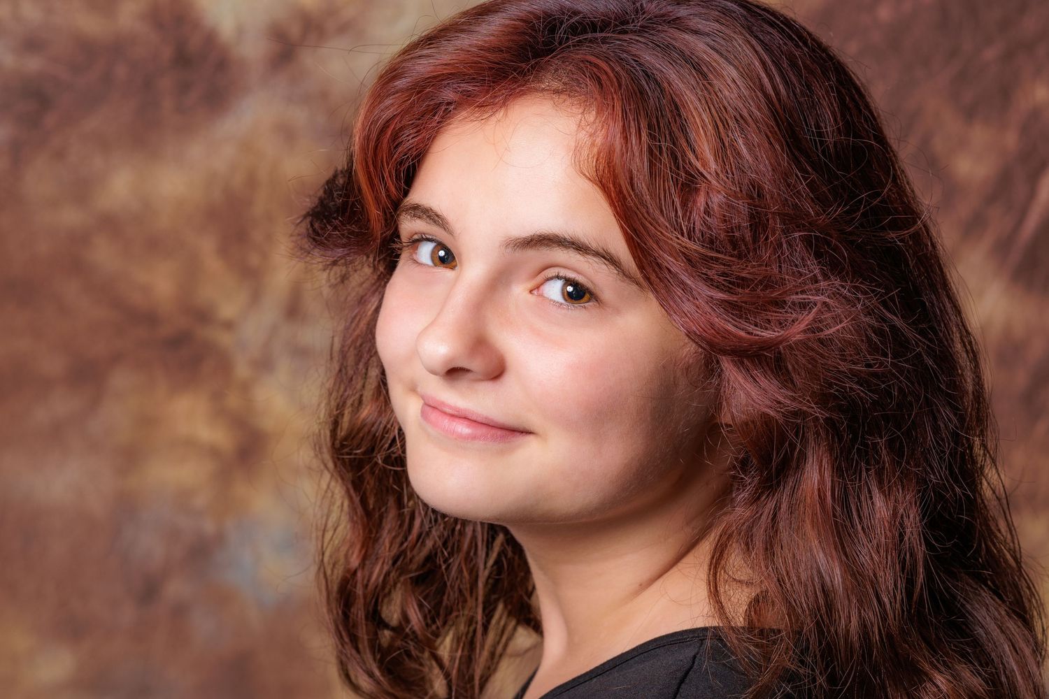 Professional headshot with warm lighting and natural expression against textured background.