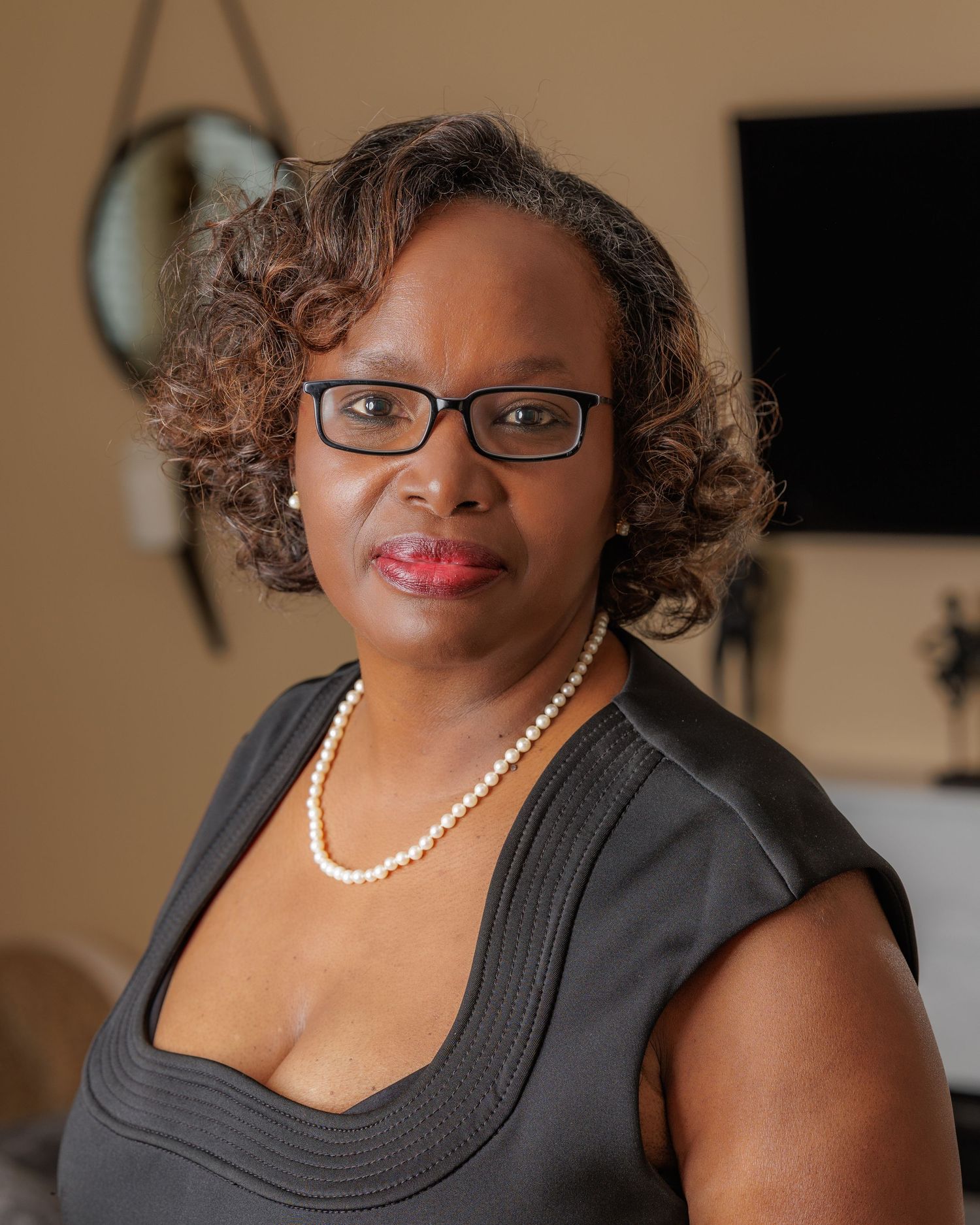 Studio portrait series featuring black sleeveless top and pearl necklace against warm background.