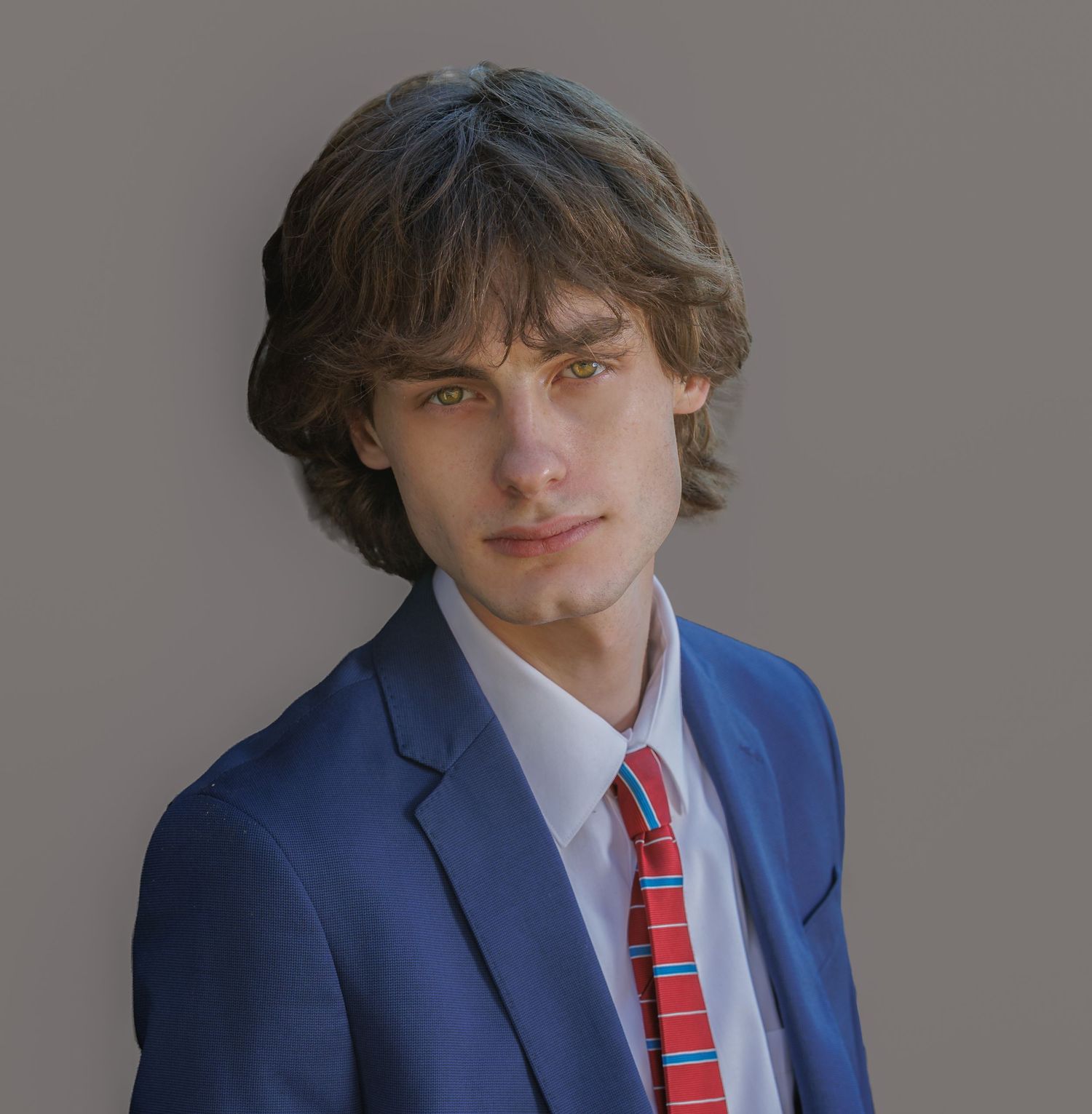 Portrait series showing someone in a blue suit and striped tie against a grey studio backdrop.