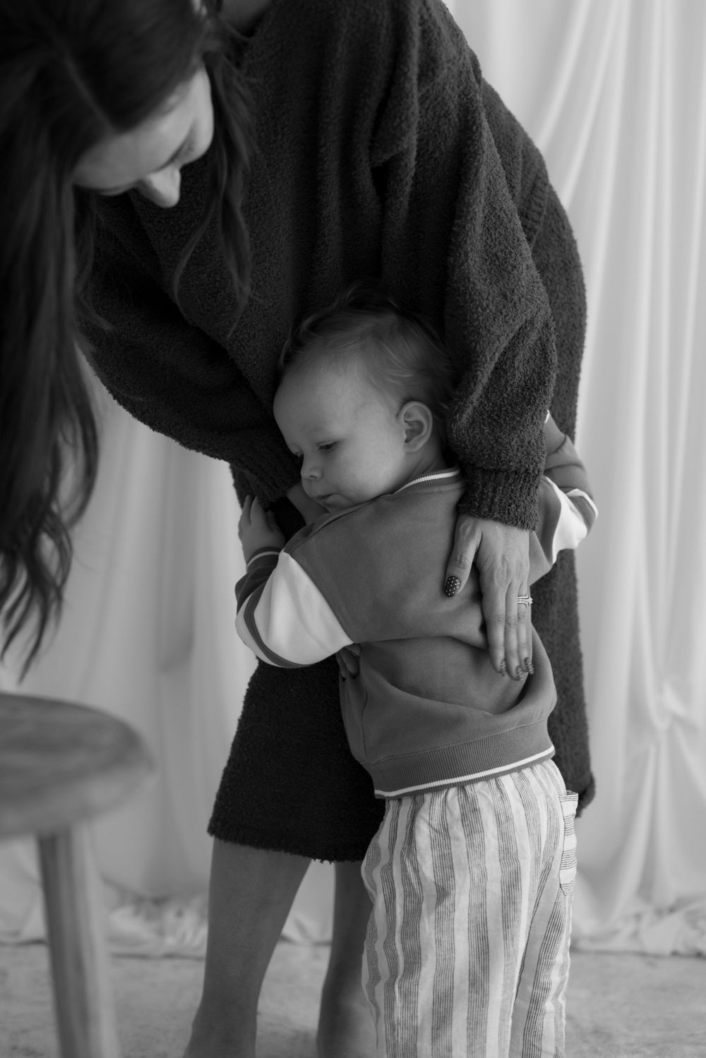 A mother gently holds her sleeping newborn baby in a tender black and white portrait.