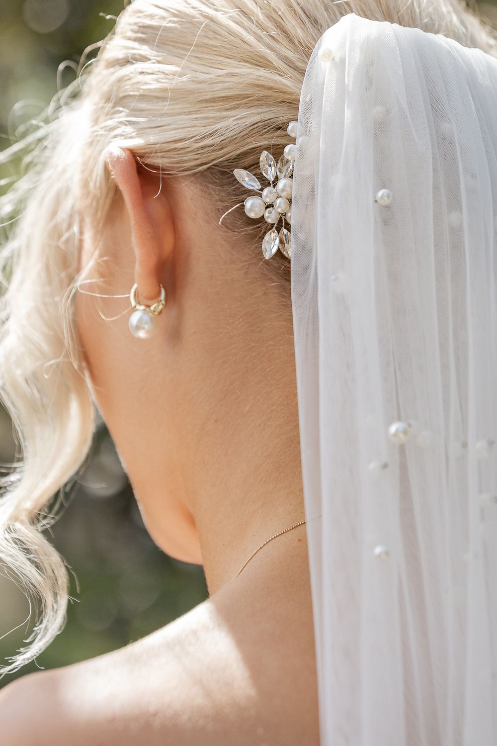 Detaljbild av brudens håruppsättning, örhänge och brudslöja