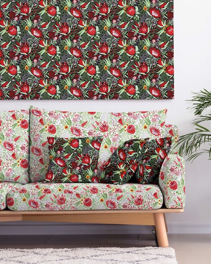 Floral sofa and matching pillows with red tropical flowers, beside a coordinating wall art print in a modern living room.