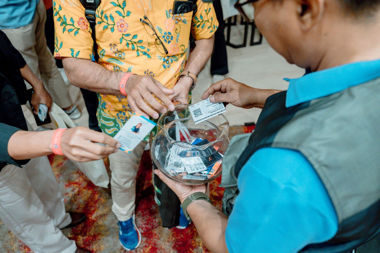 Group of people placing money into a glass bowl during a traditional ceremony or celebration event.