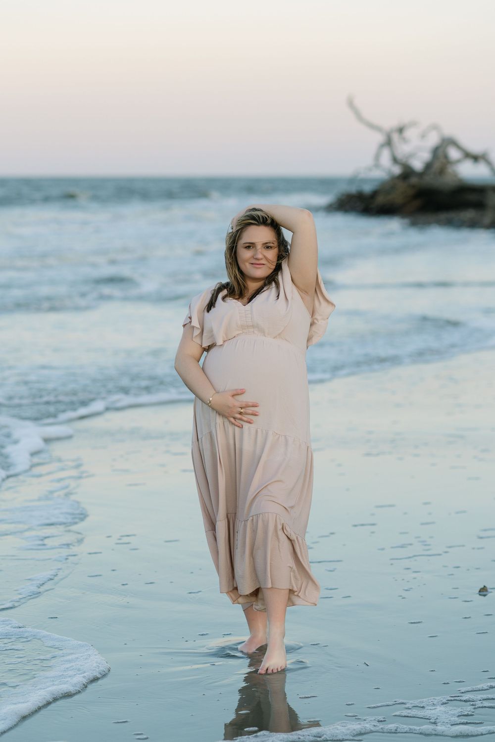 Expectant mother standing barefoot at the water’s edge during a Jekyll Island maternity session.