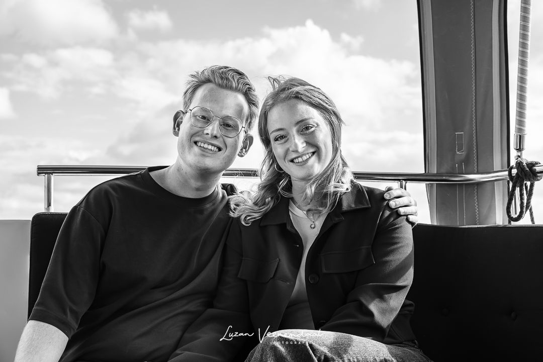Zwart-witfoto van broer en zus samen op de bank aan de achterzijde van de boot tijdens de familiefotoshoot in Uitgeest
