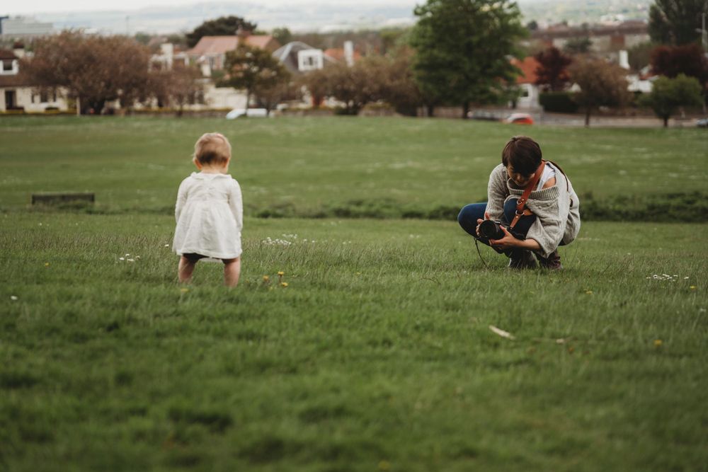 Two people sitting in a grassy field during a casual outdoor photography session.