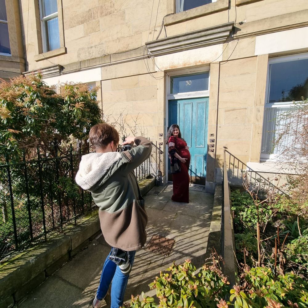 Behind the scenes photo of a photographer at work outside a building with blue door.