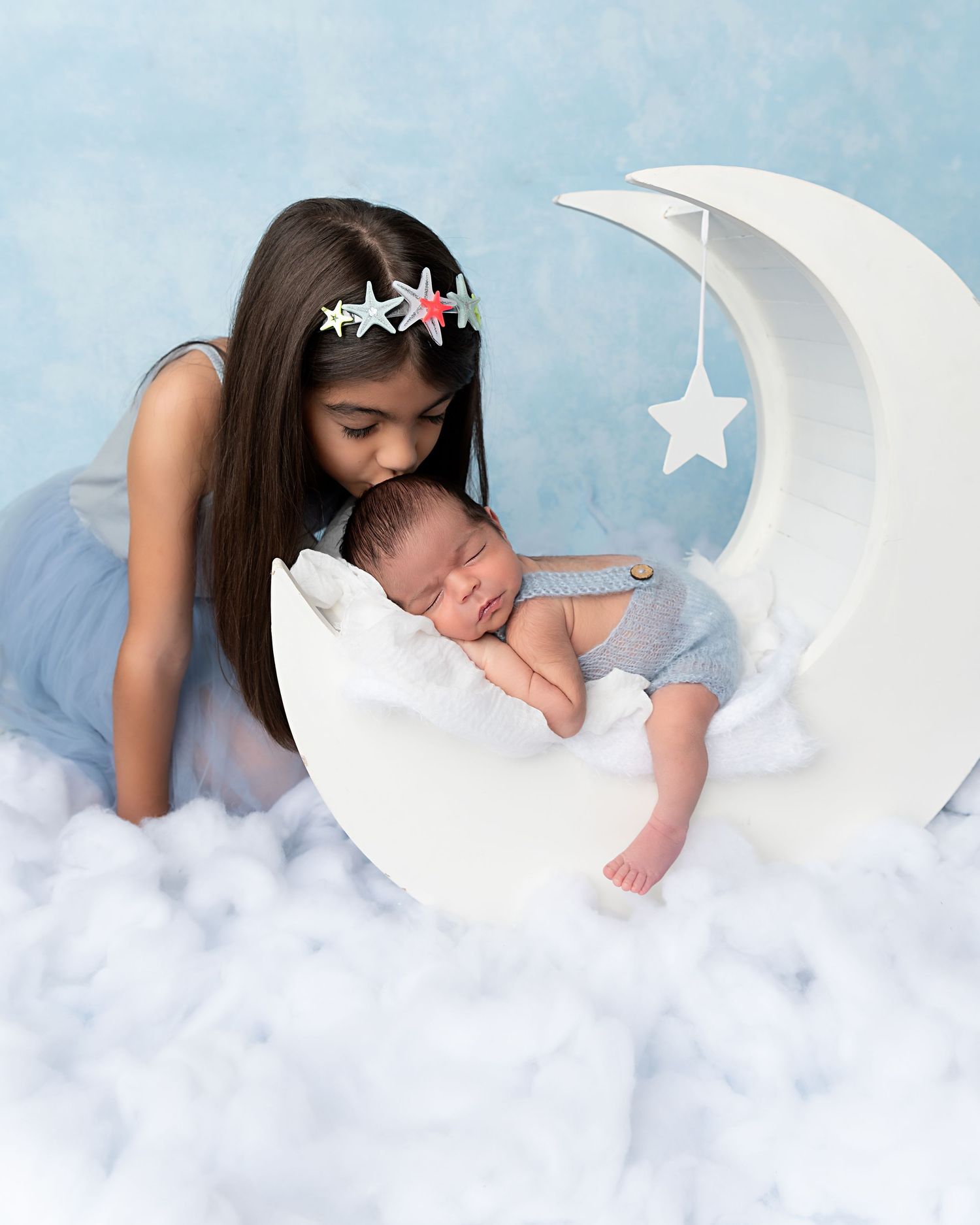 Older sister gently kisses her newborn baby brother during a sibling newborn photography session in Zephyrhills, Florida