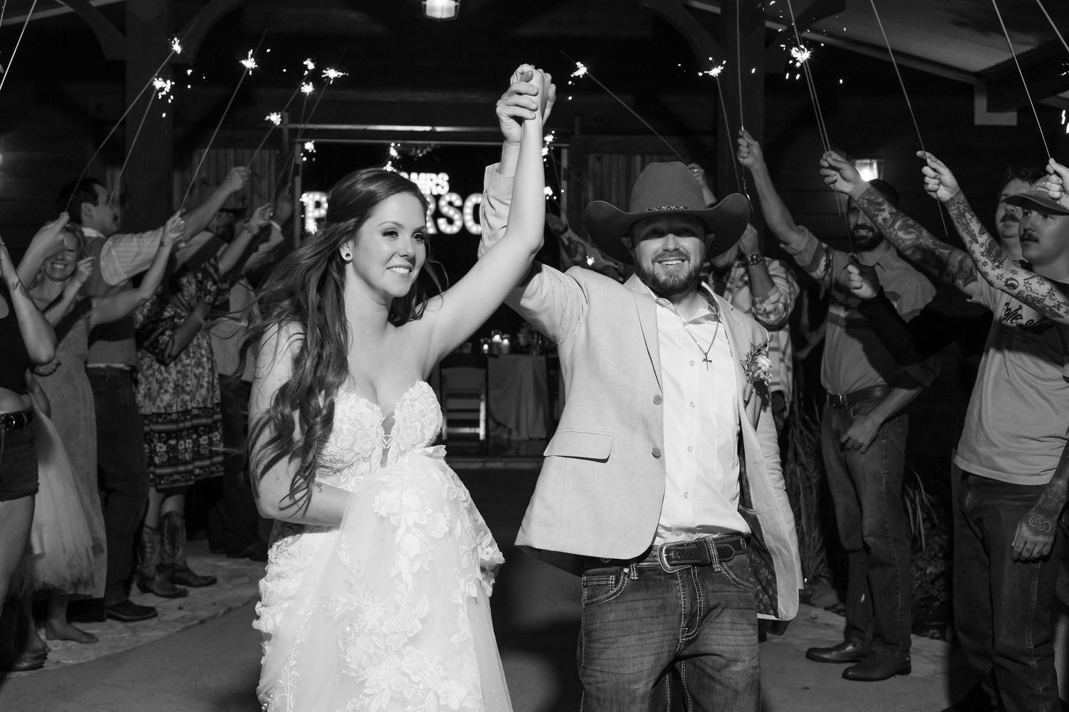 Bride and groom exit wedding ceremony through cheering guests tossing white flower petals outdoors.