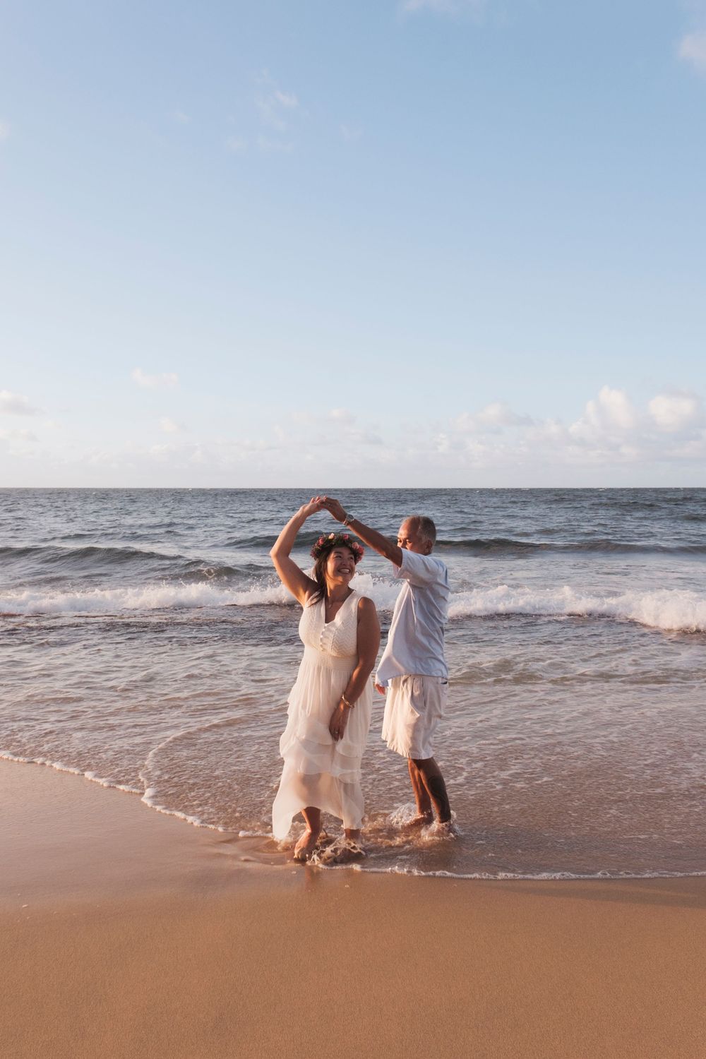 Couple dancing barefoot in the ocean during a North Shore Oahu sunset session