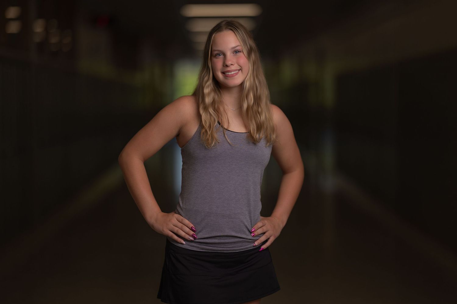 Senior portrait of a smiling blonde girl photographed with dramatic lighting