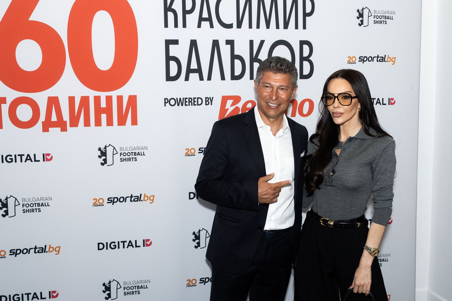 A man and woman pose together at Krasimir Balakov's 60th birthday celebration event backdrop.
