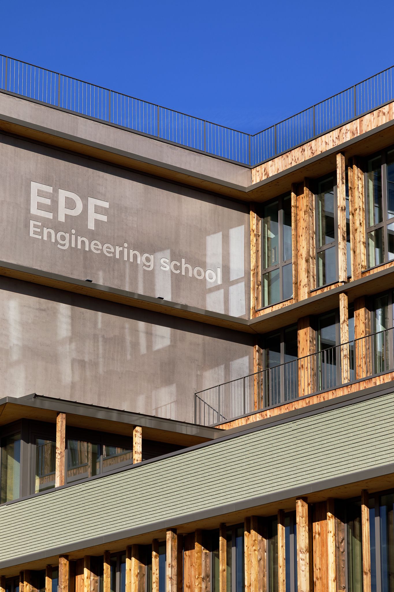 Détail de la façade d'angle de l'école d'ingénieurs EPF, montrant des ailettes verticales en bois et une signalétique sur le mur en béton.